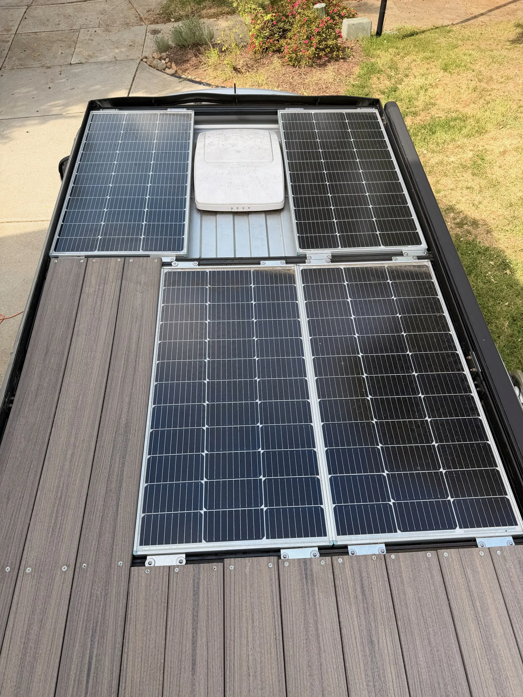 Roof from above: four solar panels around a vent fan, composite deck at the rear of the rack