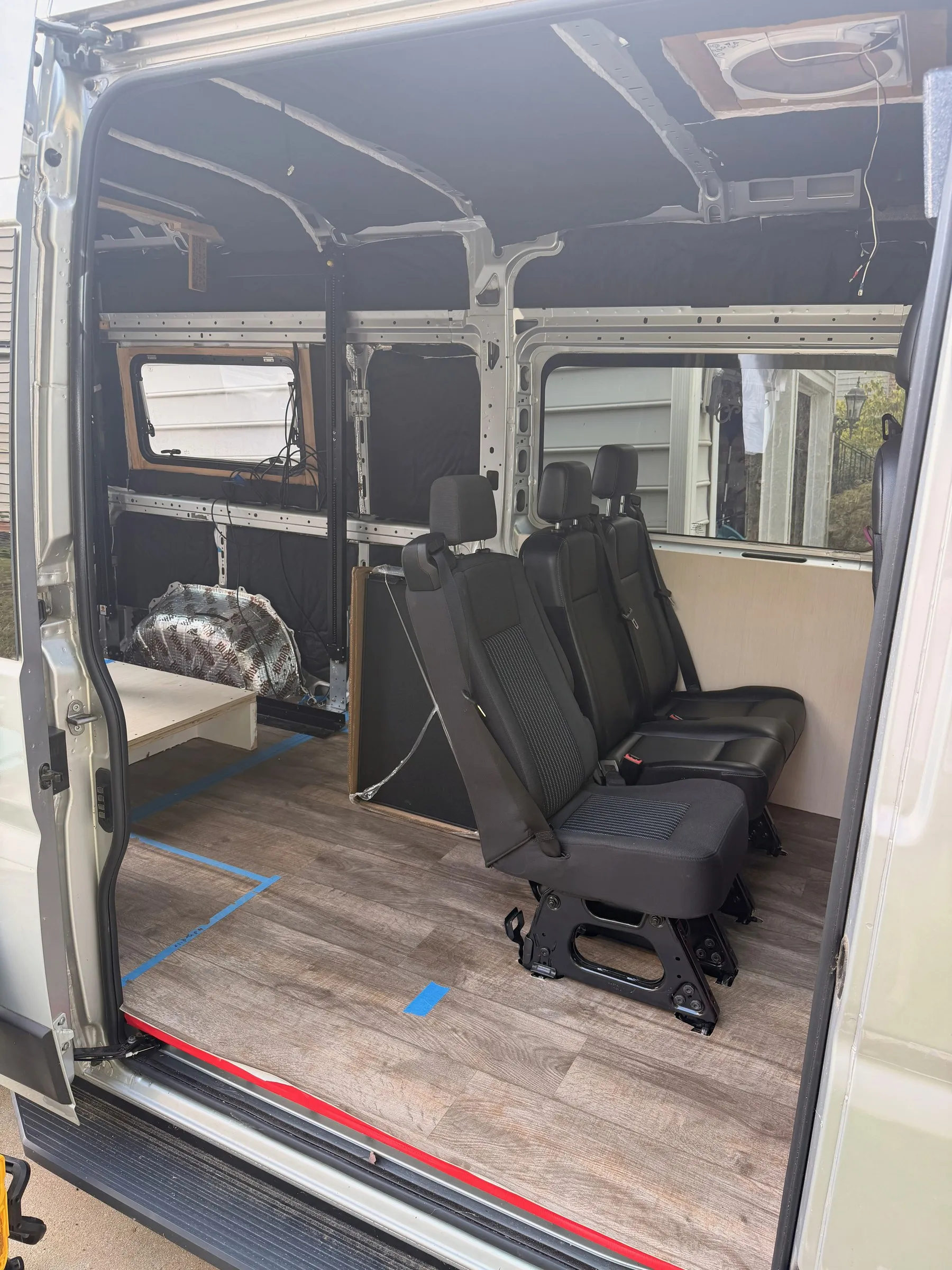Interior seen through the open sliding door, showing rear passenger seats, plank flooring and insulated walls